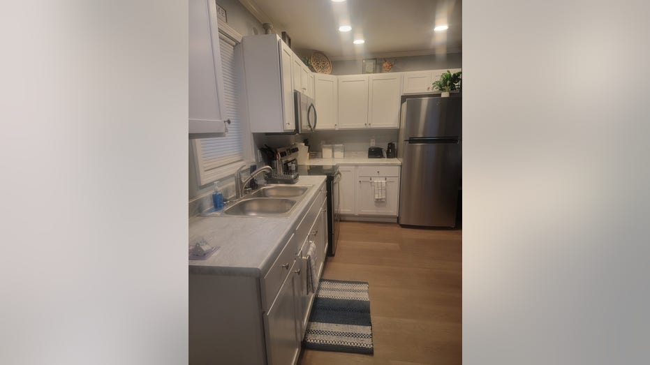 a picture of a kitchen with a sink, fridge and a rug